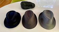Group view of three fedoras and one flat cap on table