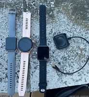 Front view of three smartwatches and charger