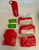 Group shot showing water bottle, two luggage tags, four packaged ponchos, knapsack
