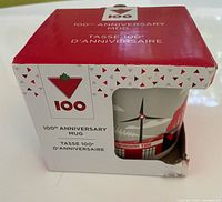 Mug in original box, front view showing 100th Anniversary logo and corner damage
