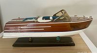 port side view of wooden speedboat on stand