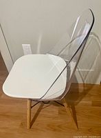 Front angled view showing acrylic back, white seat, wood legs