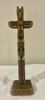 front view of carved and painted wood totem pole on square base