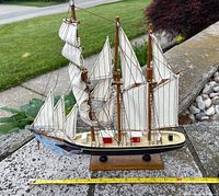 Port side view of full model showing hull, sails and stand with measuring tape for length