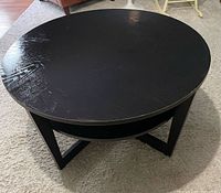 Full view of round black coffee table top showing scratches
