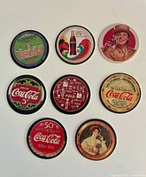 Front view of eight Coca-Cola Coke Cap discs