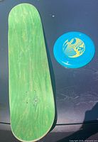 Full view of skateboard deck and Frisbee showing overall condition