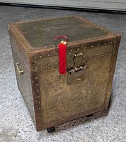 Three-quarter view of chest showing brass panels, rivets, latch with red tassel