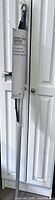 Packaged floor squeegee and 5 ft pole leaning against door