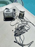 Hayward TigerShark pool cleaner with power supply and cord on pool deck