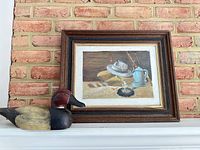 Framed painting and duck decoy on mantel