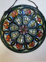 Full view of round stained glass panel showing design and chain