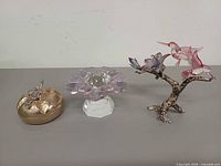 Front view of three items: metal trinket box, crystal flower, hummingbird sculpture