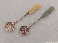 Front view of both spoons showing jade handles and Aztec calendar bowls