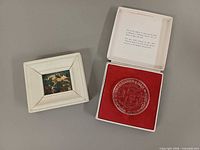 Medal in open box beside framed miniature painting