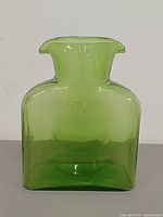 Front view of green glass water bottle showing square shape and overall condition