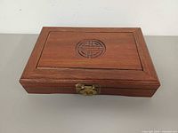 Closed rosewood jewelry box top view showing carved symbol