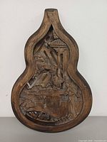 Front view of gourd-shaped carved plaque showing full relief scene