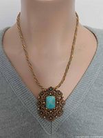 Pendant-brooch worn on chain around mannequin neck displaying size and appearance
