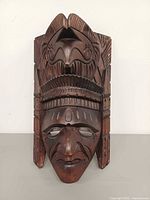 Front view of carved wood mask showing face and headdress