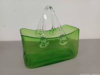Front view of green glass purse vase showing clear handles and medallions