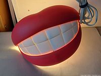 Lamp illuminated showing red lips and lit white teeth grid with attached cord visible