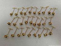 Full layout of 28 gold-tone RCAF tie tack pins arranged in rows
