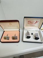 Both cufflink pairs, tie tack and boxes displayed