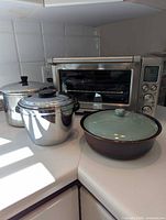 Front view of Breville toaster oven beside two stainless pots and Red Wing casserole