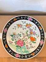 Full view of circular Famille Rose porcelain charger on cardboard background