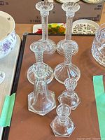 All seven clear glass candlesticks grouped, showing twist stems and hexagonal bases