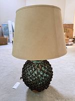 Full view of lamp showing glass base, rope netting and shade