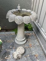 Full view of pedestal birdbath with bird ornament on rim and rabbit statue at base