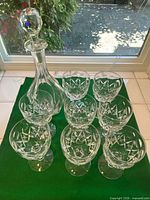 Group shot of eight goblets with decanter and stopper on green surface