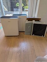 Two white Levoit air purifiers beside boxed replacement filters