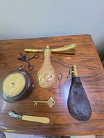 Group shot showing all items: barometer, atomizer, powder flask, key, knife, wick trimmer, loop tool
