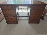 Front view showing drawers, cabinet door, kneehole stretcher