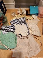 Overview of assorted baby garments, blankets, shoes, toy and accessories laid out on floor