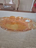 Side view of marigold carnival glass dish showing iridescence and pattern