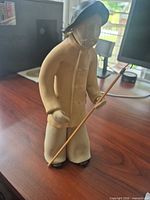 Front view of clay fisherman figurine holding rod
