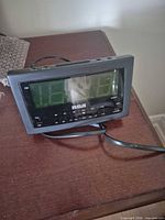 Front view of RCA digital alarm clock radio showing brand logo, LED display, frequency scale and power cord