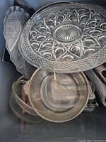 Various clear glass platters and bakeware stacked in bin
