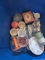 Overview of blue bin showing assorted glassware, plate, candlestick and boxed servers
