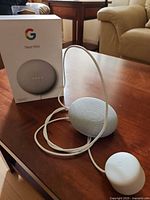 Google Nest Mini speaker with power adapter and box on table