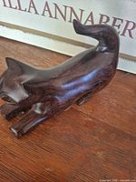 Left side view of ironwood cat figurine showing polished wood grain and stretching pose