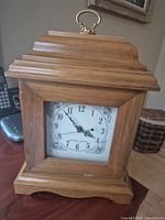 Front view of wooden mantel clock showing dial and case
