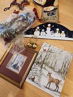 Group of wall décor including wrapped wreath, fabric banner, snowman plaque, bells, two prints