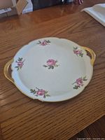 Top view of round Limoges tray showing rose pattern and gold handles