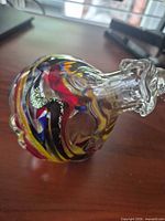 Side view of multicolour art glass ornament showing swirled colours and silver foil