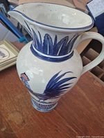 Full view of blue and white rooster pitcher showing spout, handle and decoration